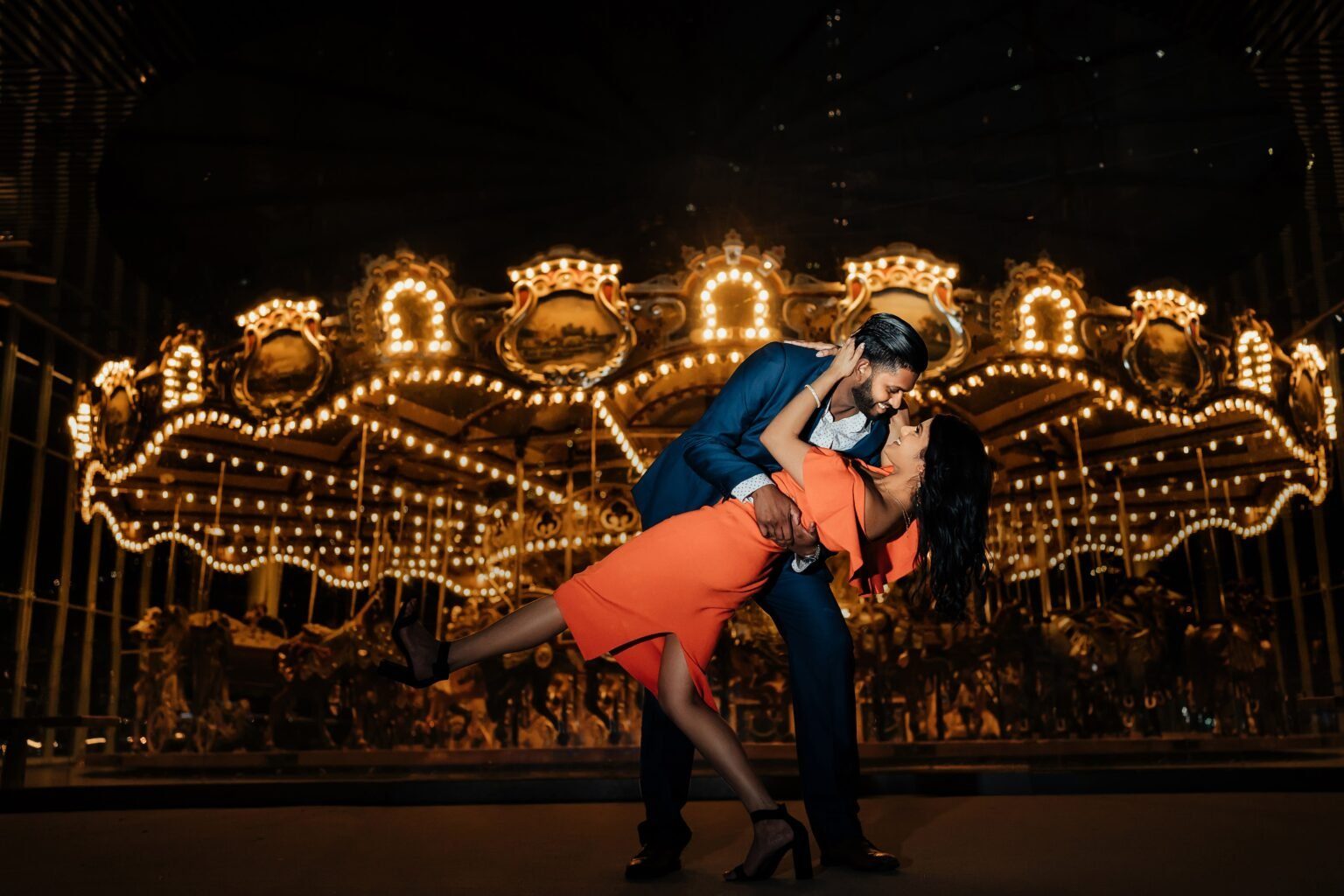 Couple by a glowing carousel at night