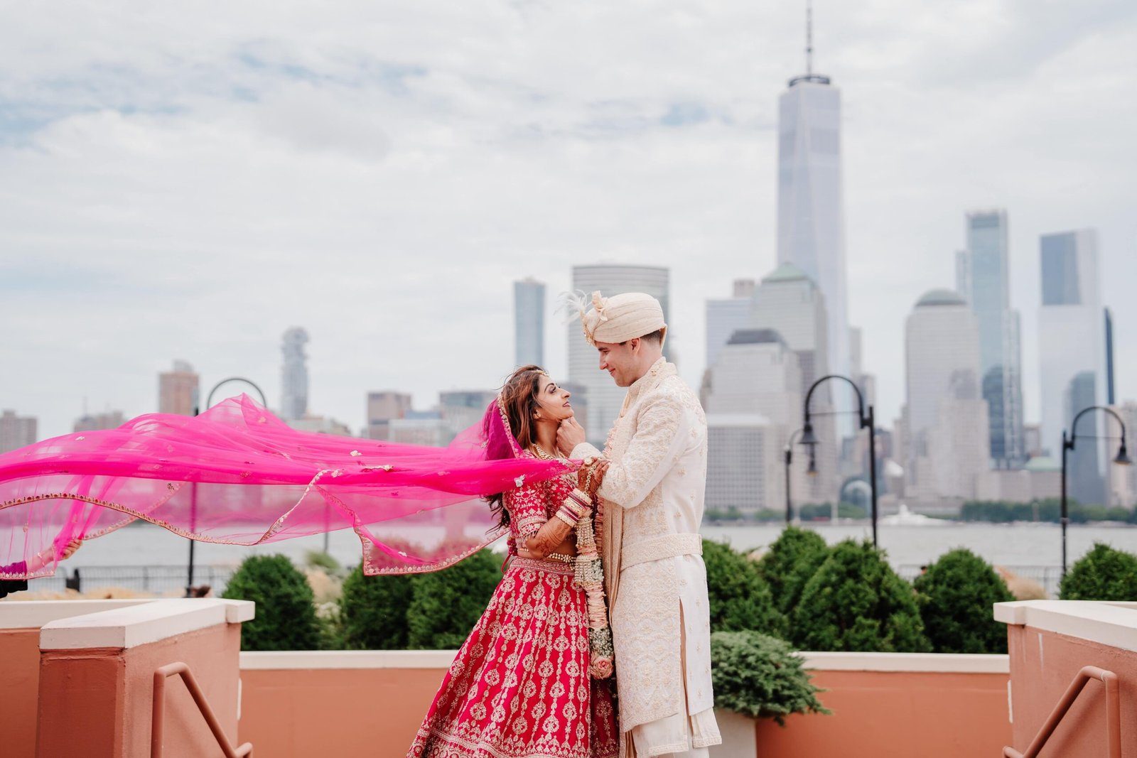 Bride and groom with a flowing pink dupatta against the Manhattan skyline